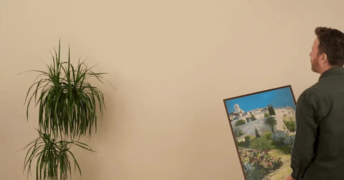 A framed Didier Breteau painting being hung on a wall at home
